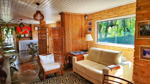 a living room with a couch and a desk and a window at Pousada Lacosta in Ilhabela