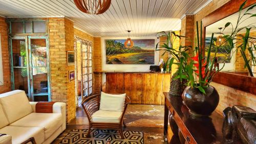 a living room with a couch and a vase with plants at Pousada Lacosta in Ilhabela