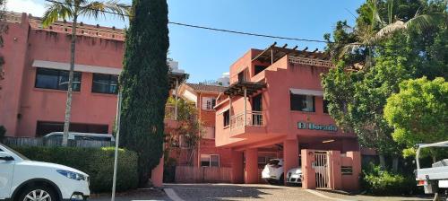 a red building with a white car parked in front of it at El Dorado Apartments in Gold Coast