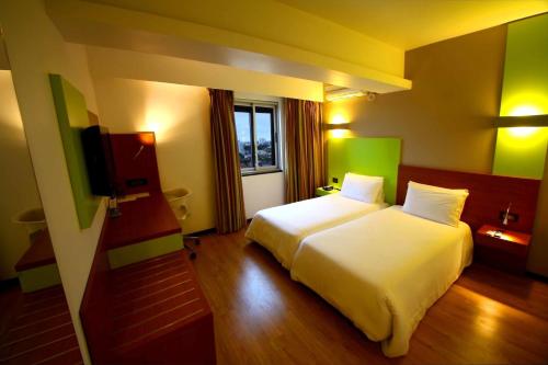 a bedroom with a white bed and a television at Hotel Africa in Maputo