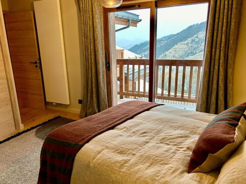 ein Schlafzimmer mit einem Bett und einem großen Fenster in der Unterkunft Appartement neuf à Méribel, proche des pistes, balcon, service concierge inclus! - FR-1-613-103 in Les Allues