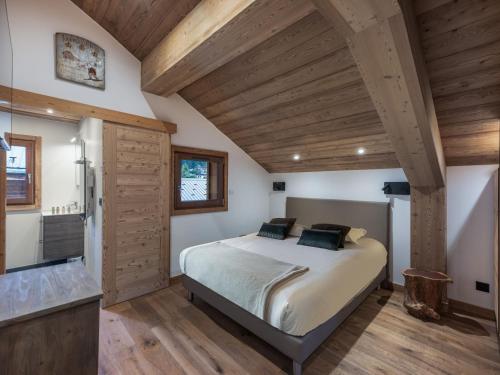 une chambre avec un lit dans une pièce avec des plafonds en bois dans l'établissement Appartement rénové au centre de Megève avec balcon et parking - FR-1-569-137, à Megève