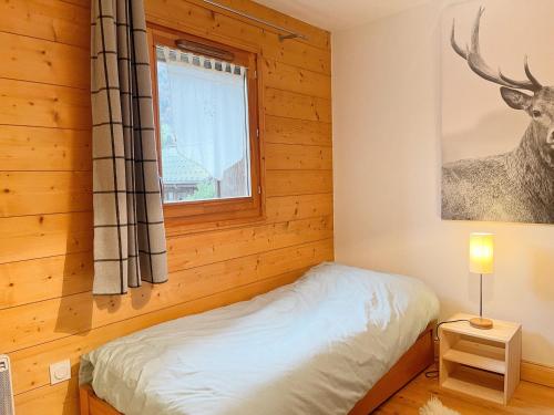 une chambre avec un lit et une fenêtre dans l'établissement Appartement cosy avec piscine, terrasse et parking, proche du centre et des commodités, arrêt ski-bus à 50m - FR-1-624-149, à Samoëns