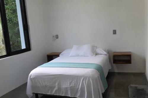 a white bed in a room with a window at Casa Chikatana un lugar familiar y elegante a pasos de la playa Bacocho in Puerto Escondido