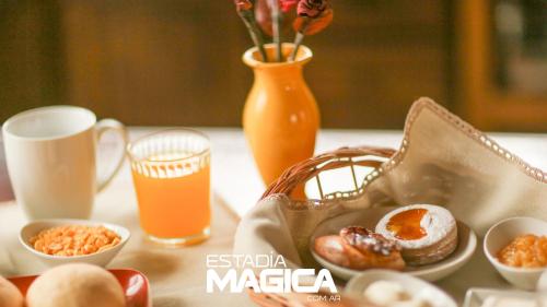 une table garnie de produits pour le petit-déjeuner et d'un verre de jus d'orange dans l'établissement Cabañas en Malargue, à Malargüe