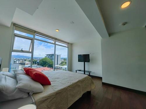 ein Schlafzimmer mit einem Bett und einem großen Fenster in der Unterkunft 706 Torres Los Yoses Hermoso apartamento en Barrio Escalante con Parqueo in San José