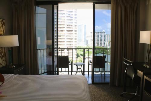a hotel room with a bed and a balcony with a view at Elevated Aqua Palms Waikiki Studio condo in Honolulu