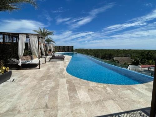トゥルムにあるPENTHOUSE CON ALBERCA PRIVADA Y ROOFTOP (MENESSES TULUM)のパティオ(青い水のスイミングプール付)