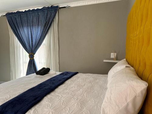 a bedroom with a bed with a blue curtain and a window at Dee Park Entertainment Centre in Thohoyandou