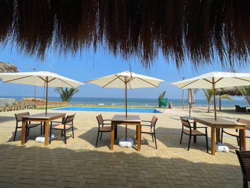 een groep tafels en stoelen met parasols op het strand bij Hotel Gran Azul Bungalows in Canoas De Punta Sal