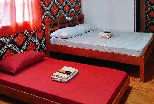 RedDoorz @ Boondocks Cabins Resort في Dalumpinas Oeste: غرفة نوم بسريرين ومقاعد حمراء مع محفظة