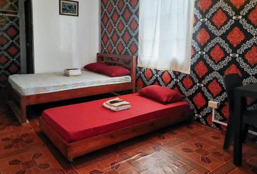 RedDoorz @ Boondocks Cabins Resort في Dalumpinas Oeste: غرفة بسريرين مع شراشف حمراء ونافذة
