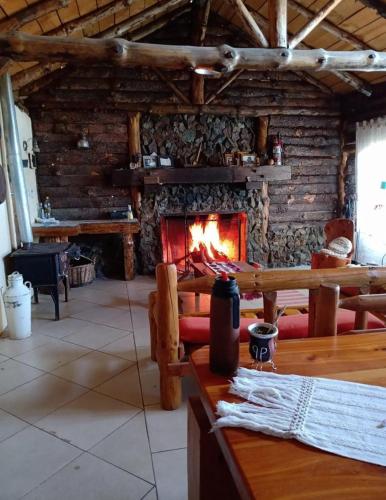 a living room with a fireplace in a log cabin at Complejo Turistico PET Friendly Los Abuelos Montañas Serenas in Cholila