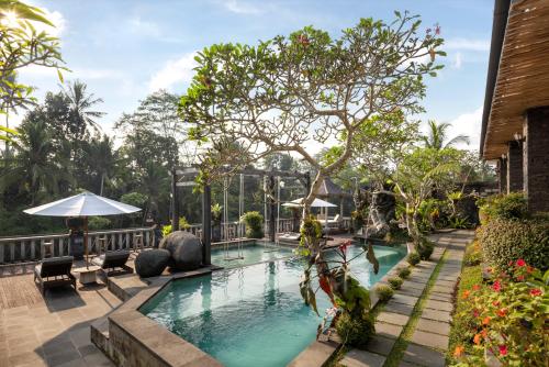 a swimming pool at a resort with a tree at Kawi Resort A Pramana Experience in Tegalalang