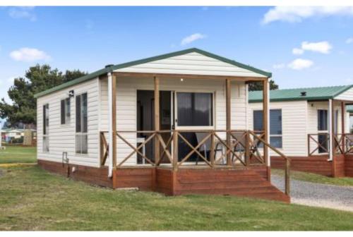 a small white house with a porch on a yard at Discovery Parks - Devonport in Devonport