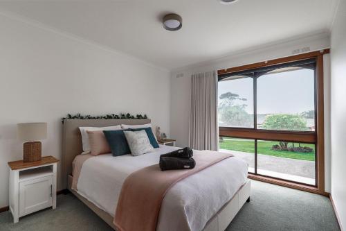 - une chambre avec un grand lit et une grande fenêtre dans l'établissement Sun Rise Escape Inverloch, à Inverloch