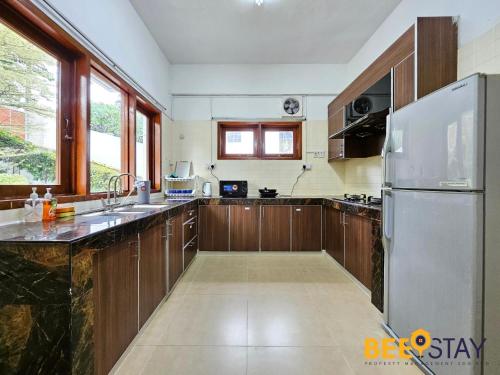 a kitchen with wooden cabinets and a stainless steel refrigerator at Bangsar Three Storey Luxury Landed House 19PAX in Kuala Lumpur