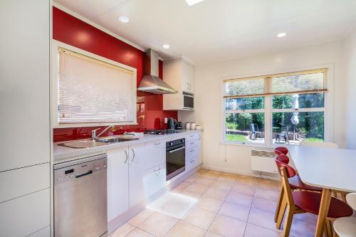 a kitchen with red walls and white cabinets and a table at Sunny Richmond Retreat in Richmond