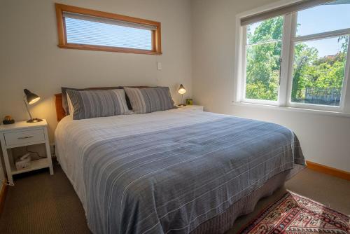 a bedroom with a large bed and two windows at Brougham Street B and B in Nelson