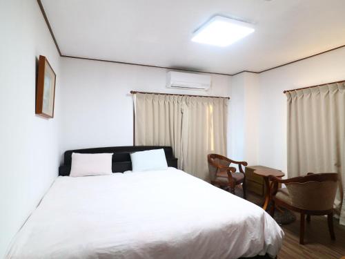 a bedroom with a white bed and a table and chairs at ゴールデンビーチホテル in Katakai