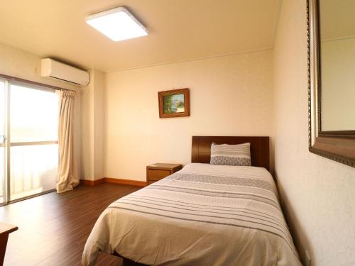 una camera con un letto in una stanza con una finestra di ゴールデンビーチホテル a Katakai