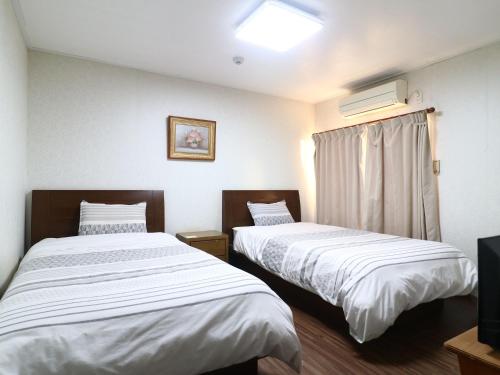 a room with two beds and a television in it at ゴールデンビーチホテル in Katakai