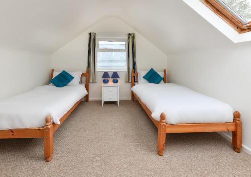 two twin beds in a room with a window at 10 Llwyn Onn Beach Hut in Abersoch