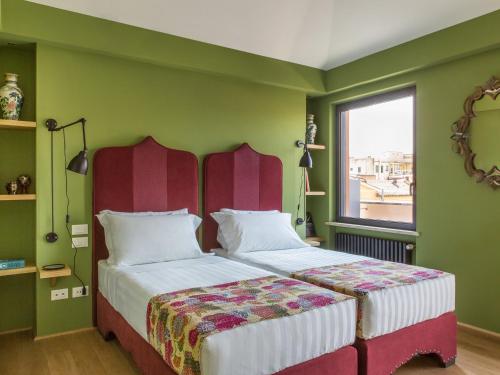 a bedroom with two beds with green walls and a window at Rarity Suites in Rome