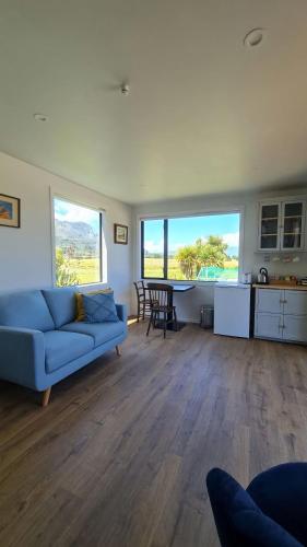 a living room with a blue couch and a table at Beach Break Cabin 2 in Pohara