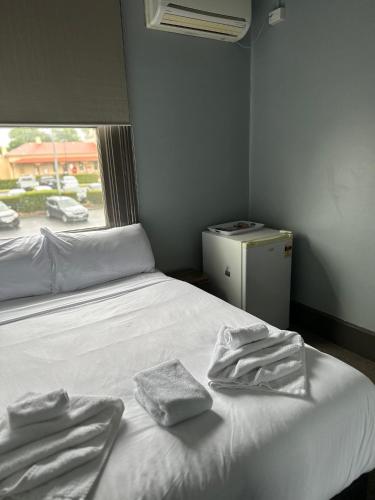 a bedroom with a white bed with two towels on it at The Great Western Hotel in Orange