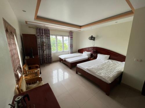 a hotel room with two beds and a window at Khách Sạn Hồng Hảo in Lao Cai
