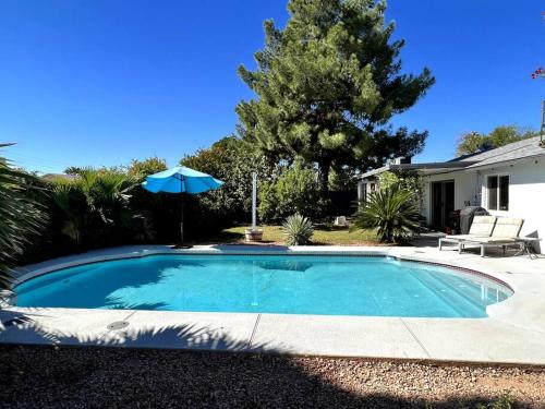 a swimming pool with an umbrella next to a house at Desert Oasis- *Pool and Hot Tub* in Phoenix