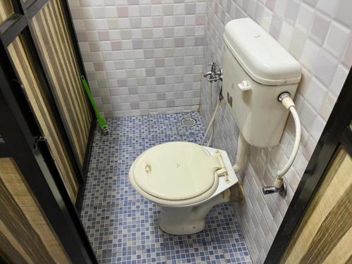 a bathroom with a toilet in a tiled room at SAHAY VILLA RESORT in Durbate