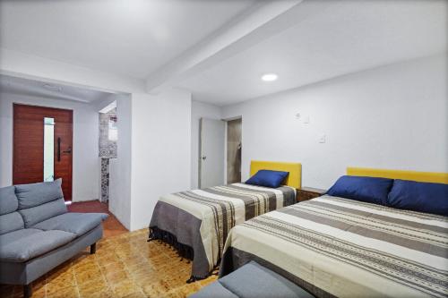 two beds in a room with a couch and a chair at Casa Nance Alojamientos XAMAN HÁ Centro Mercado 28 y ADO Suite Familiar 3 Personas in Cancún