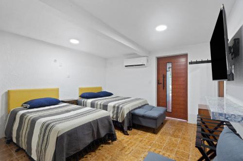 a room with two beds and a flat screen tv at Casa Nance Alojamientos XAMAN HÁ Centro Mercado 28 y ADO Suite Familiar 3 Personas in Cancún