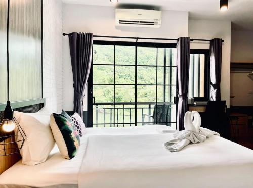 a bedroom with a white bed with a large window at PP GRAND KAMALA HOTEL-SHA Extra Plus in Kamala Beach