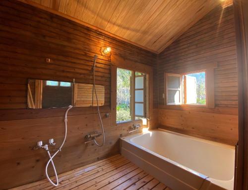 a bathroom with a tub in a wooden wall at Log Cottage Yamanohiroba - Vacation STAY 40692v in Shiso