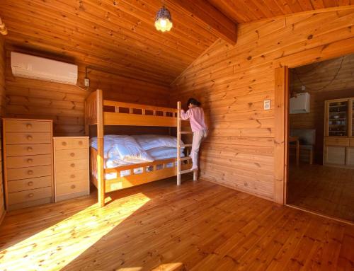 une femme debout sur un lit superposé dans une cabine dans l'établissement Log Cottage Yamanohiroba - Vacation STAY 40692v, à Shiso