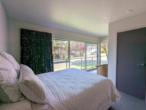 a bedroom with a bed and a large window at The Coastal Getaway in Mount Maunganui