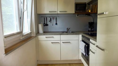 een keuken met witte kasten, een wastafel en een raam bij Ferienwohnung Margit in Förolach