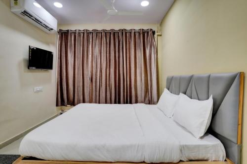 a bedroom with a white bed with a window at OYO Hotel 7 Star in Surat