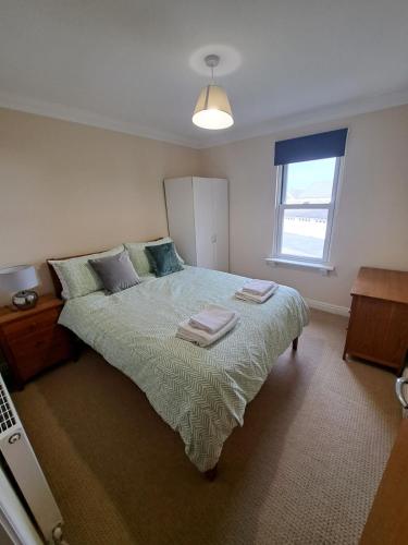 a bedroom with a bed with two towels on it at The Elms Apartments Ramsey Isle of Man UK in Ramsey