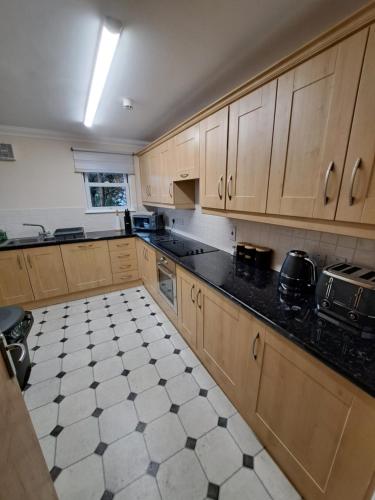 una cocina con armarios de madera y encimeras negras en The Elms Apartments Ramsey Isle of Man UK en Ramsey