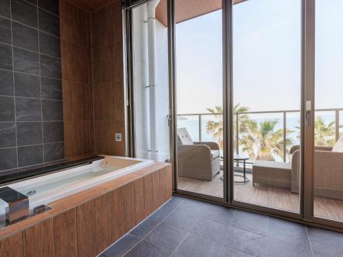 a large bathroom with a tub and a patio at Alba HOTEL & Glamping in Nishinoura