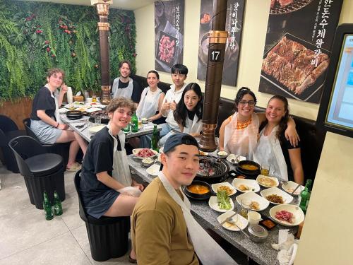 a group of people sitting at a table with food at Hithere City Myeongdong in Seoul
