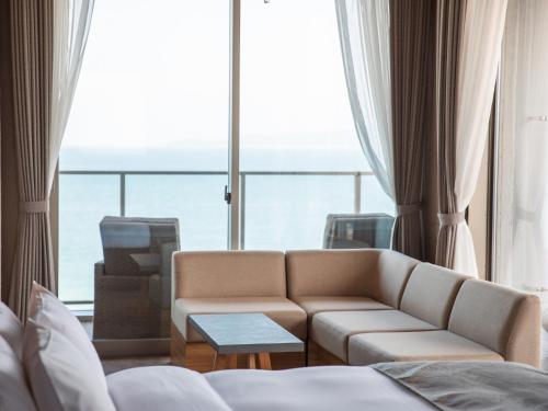 a living room with a couch and a large window at Alba HOTEL & Glamping in Nishinoura