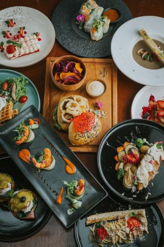 a table topped with plates of food on plates at The Hava Ubud A Pramana Experience in Ubud