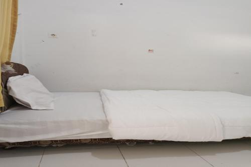 a white couch sitting against a white wall at Hotel O Elang Homestay in Parit