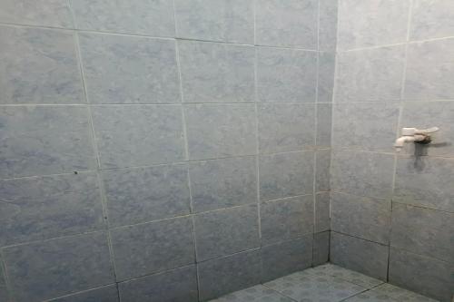 a bathroom with a gray tiled wall and a toilet at SPOT ON 93375 Elang Homestay in Parit
