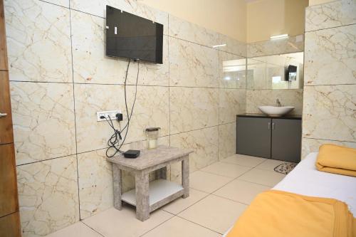 a bathroom with a bed and a tv on a wall at Blue Pearl Beach Guest House in Māvalli